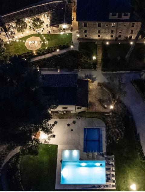 Veduta notturna di una villa con piscina illuminata e giardino per eventi.